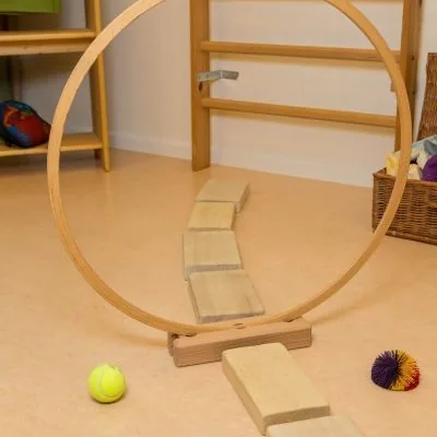 Parcours aus Holzbrettern und einem Holzreifen auf dem Boden des Therapieraums