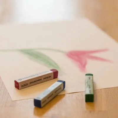 Pastellkreiden neben einer gemalten Tulpe auf Papier